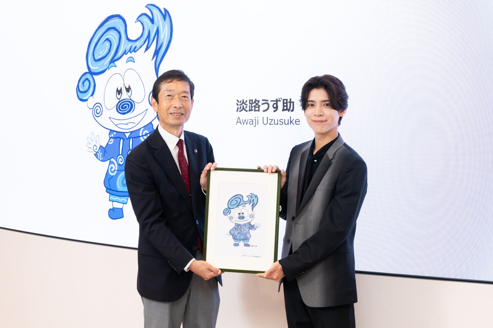 「淡路うず助」のサイン入り原画を守本憲弘南あわじ市長に手渡す松島聡